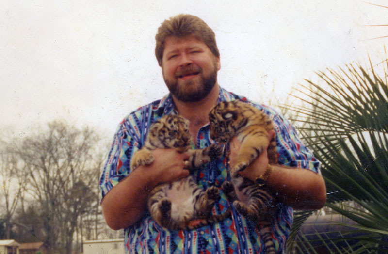 A younger Michael Sandlin with a pair of tiger cubs, courtesy TigerTruckStop.com. 