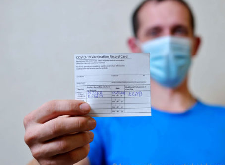 Man with COVID-19 vaccination record card