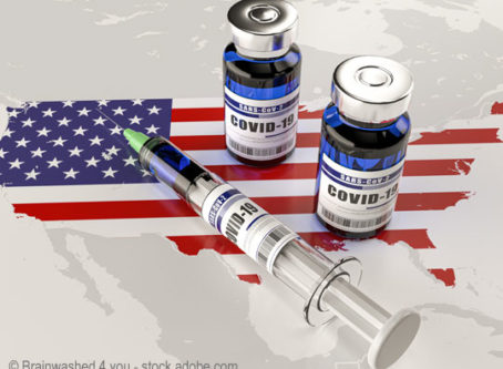 A syringe and two bottles of COVID-19 vaccine on USA map.