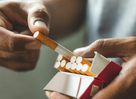 Male holding a pack of cigarettes. Image by Nopphon