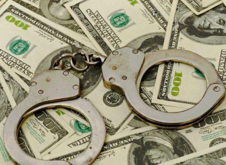 Handcuffs on money background Image by Natalia Merzlyakova